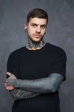 Serious tattooed young man with piercing in his ears and nose looking at camera | Photo