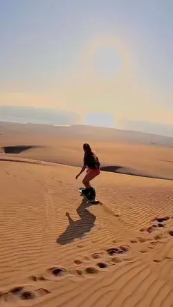 Watch she ride with a sandboard at sunset in Caramucho Dune, Iquique, Chile
